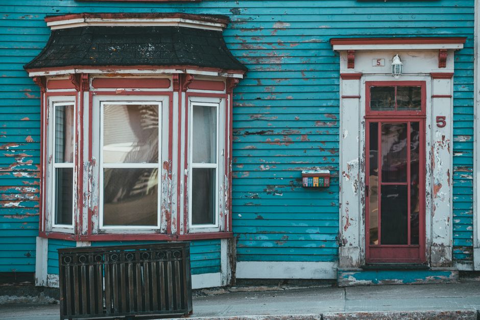 A painted house wall with a door and window under a clear sky