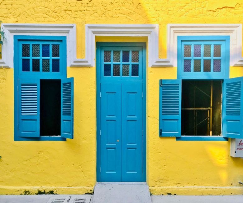 A painted house wall with a door and window under a clear sky